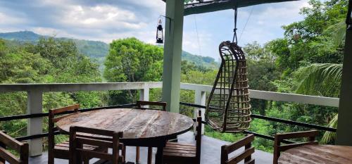 um alpendre com mesa e cadeiras e vista para as montanhas em Green Leaf Holiday Bungalow em Ratnapura