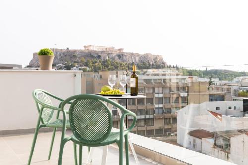 a table and chairs on a balcony with a bottle of wine at Enattica Suites in Athens