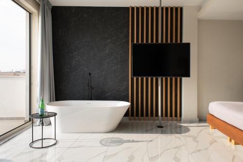 a bathroom with a tub and a tv on a wall at Enattica Suites in Athens
