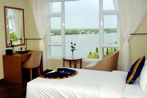 um quarto com uma cama, uma secretária e uma janela em Khách sạn Sài Gòn Vĩnh Long em Vinh Long