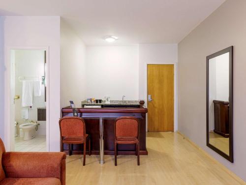 a room with a table and chairs and a bathroom at Mercure Joinville Prinz in Joinville