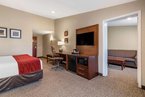 a hotel room with a bed and a desk with a television at Comfort Inn Glenmont - Albany South in Glenmont