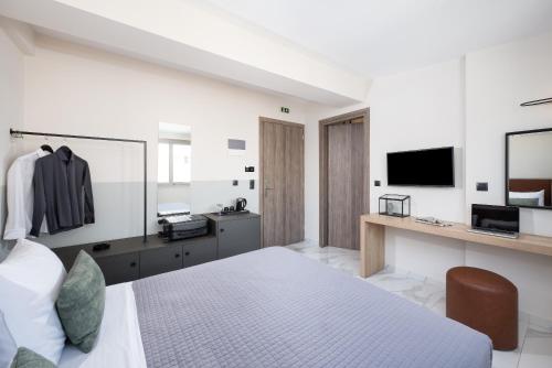 a bedroom with a bed and a desk and a television at Enattica Suites in Athens
