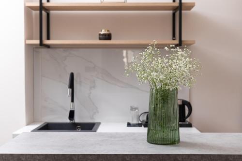 a green vase with flowers on a counter next to a sink at Enattica Suites in Athens