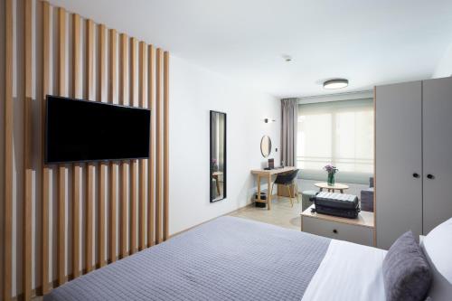 a bedroom with a bed and a tv on a wall at Enattica Suites in Athens