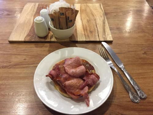 a white plate with a piece of meat on a table at Bridge View Guest House in Ironbridge