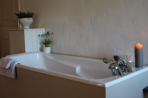 El baño incluye una gran bañera blanca con velas. en Les Romarins B&B, 10 min d'Uzès, piscine et grand jardin, Table d'hôte, en Uzès