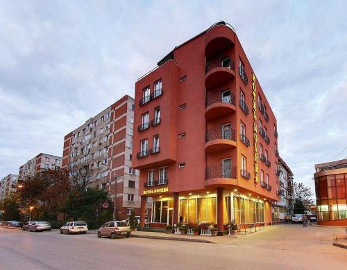 a red building with cars parked in front of it at Hotel Novera in Timişoara