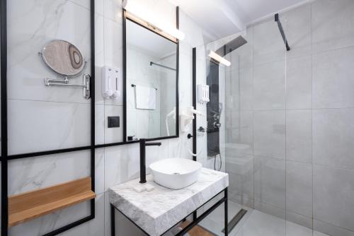 a white bathroom with a sink and a shower at Enattica Suites in Athens