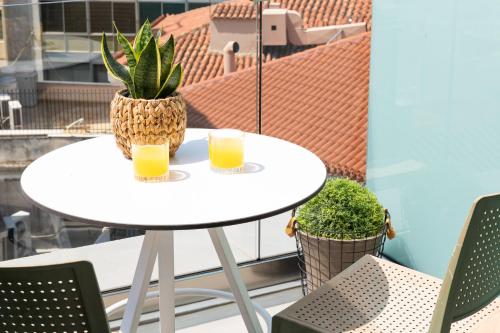 a table with two glasses of orange juice on a balcony at Enattica Suites in Athens