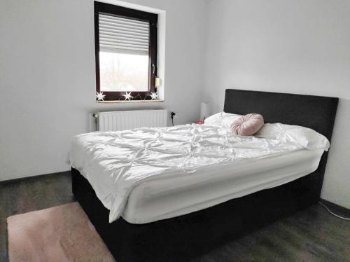 a bedroom with a large bed with white sheets and a window at Apartment am See - Borken, Hessen in Borken