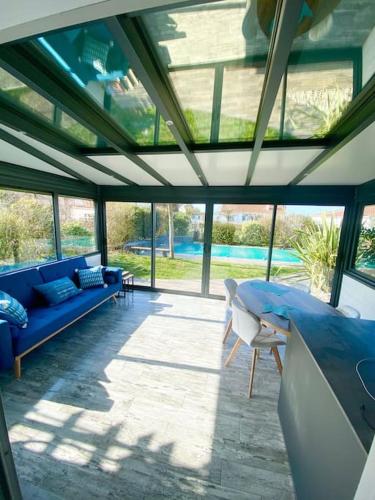 une véranda avec un canapé bleu et des chaises dans l'établissement Magnifique maison avec piscine, à Le Port-des-Barques