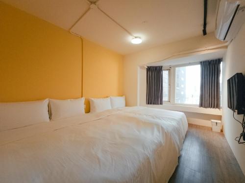 sypialnia z białym łóżkiem i oknem w obiekcie Taipei Inn w Tajpej