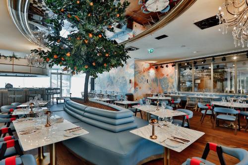 a restaurant with tables and chairs and a tree at EPIC SANA Marquês Hotel in Lisbon