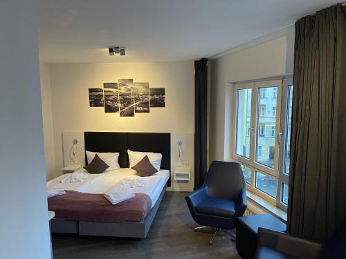 a bedroom with a bed and a chair and a window at ALFA Hotel in Berlin