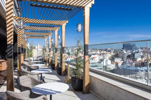 a balcony with tables and chairs and a view of the city at EPIC SANA Marquês Hotel in Lisbon