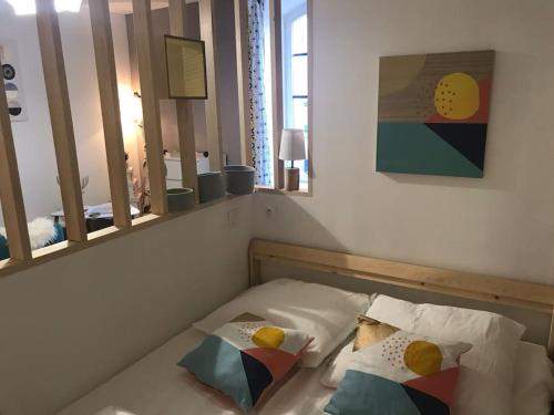 ein Schlafzimmer mit einem Bett mit zwei Kissen und einem Spiegel in der Unterkunft Milly COCOON / centre ville in Milly-la-Forêt