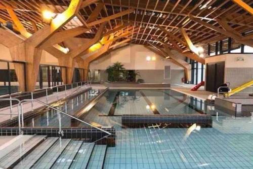 uma grande piscina interior com um grande tecto em Milly COCOON / centre ville em Milly-la-Forêt