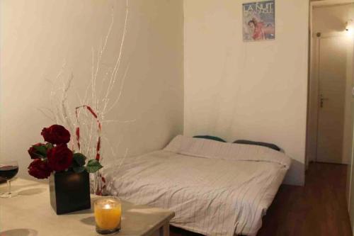- une chambre avec un lit et une table avec un vase de roses dans l'établissement Nice studio in the heart of Sceaux, à Sceaux