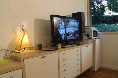 une télévision assise au-dessus d'une commode avec une lampe dans l'établissement Nice studio in the heart of Sceaux, à Sceaux
