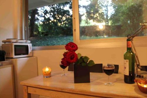 a table with two glasses of wine and a flower at Nice studio in the heart of Sceaux in Sceaux