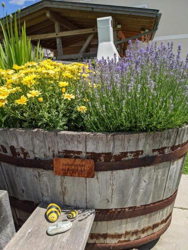 a large wooden barrel with flowers and a table at Marhof Pustertal in Anras