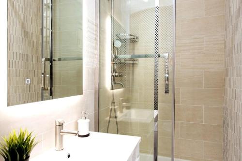 une salle de bain avec un lavabo et une douche en verre dans l'établissement Elégant 120m2 3CH quartier Romantique Centre Ville, à Paris