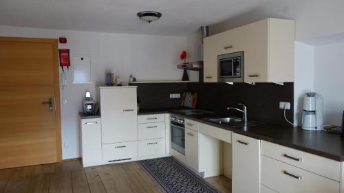 a kitchen with white cabinets and a black counter top at Marhof Pustertal in Anras