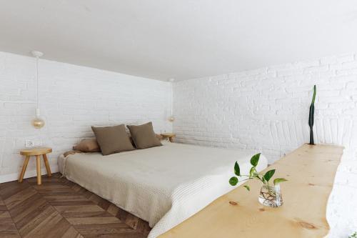 Dormitorio blanco con cama y mesa de madera en Passage Apartment, en Ivano-Frankivsk