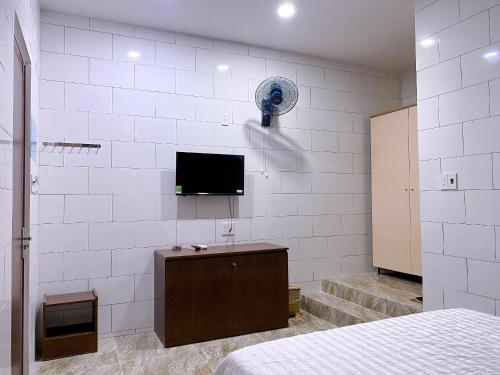 um quarto com uma cama e uma televisão na parede em Khách sạn Ngọc Bích 2 em Thôn Tân Hội