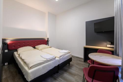 a bedroom with a bed and a table and a tv at Royale Apartaments Central City Cologne in Cologne