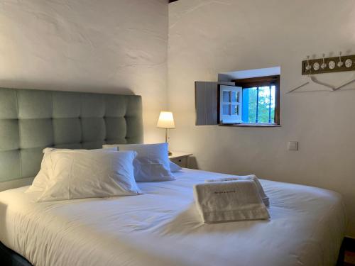 a bedroom with a large bed with white sheets and a window at RIVERSIDE RANCH by Nature Bliss in Vila Nova de Milfontes