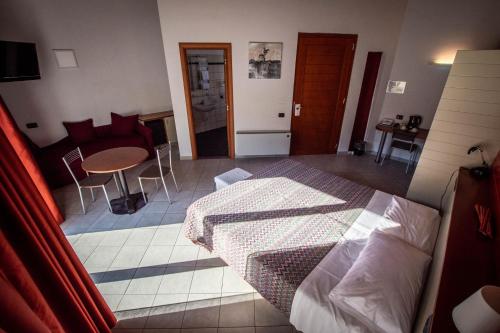 a bedroom with a bed and a table and a couch at Albavillage Hotel Wellness & Camping in Alba