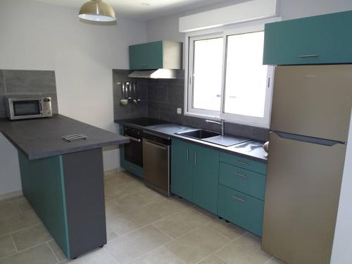 une cuisine avec des armoires bleues, un évier et une fenêtre dans l'établissement le meublé du pêcheur, à Port-Saint-Louis-du-Rhône