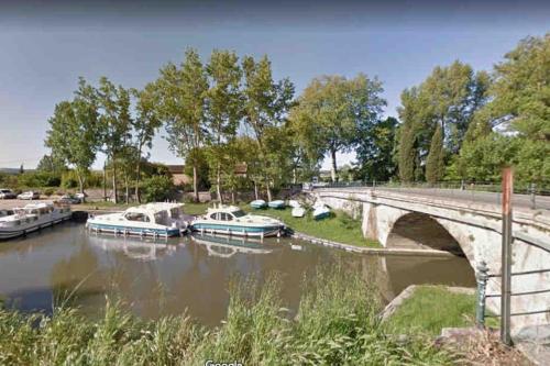 a group of boats docked in a river under a bridge at Maison atypique dans circulade in Bram