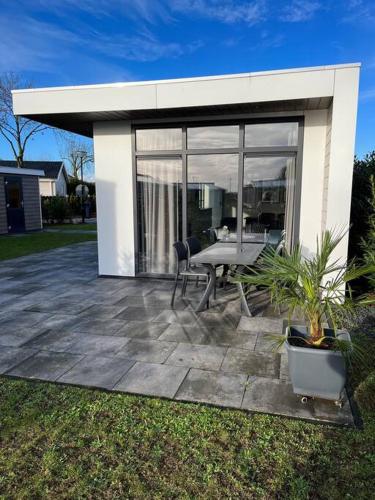 a patio with a table and chairs in front of a house at Luxus Chalet Waterfront in Lathum