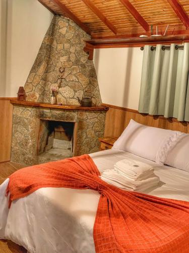 a bed with a stone fireplace in a room at Chalé Bom Jardim in Camanducaia