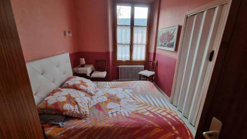 a bedroom with a bed with a comforter and a window at T2 avec terrasse vue Hautacam dans villa historique "Victoria" in Argelès-Gazost