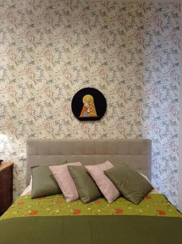 a bedroom with a bed with green sheets and a clock on the wall at Appartamento Fanciullacci in Montelupo Fiorentino