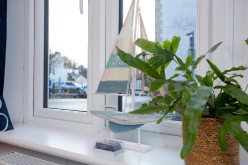 a toy boat sitting on a window sill next to a plant at Shell Cottage in Sidmouth