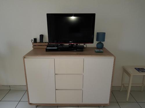 a tv on top of a white cabinet with a television at Le Garden 250 m plage du Chay in Royan