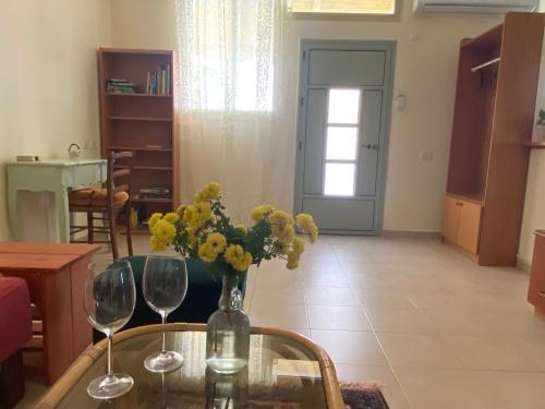 una mesa con dos copas de vino y un jarrón de flores en O&B Hospitality - אירוח אלף בית, en Dafna