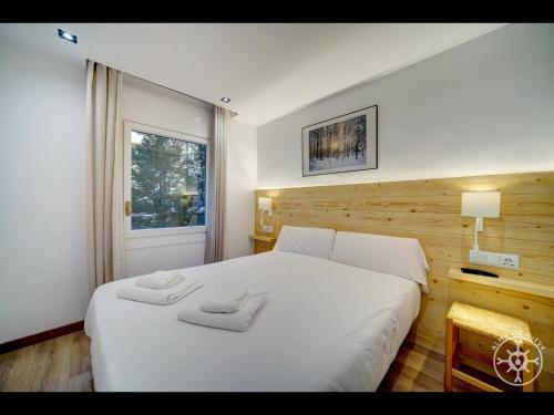 a bedroom with a white bed with two towels on it at MONTLUDE de Alma de Nieve in Baqueira-Beret