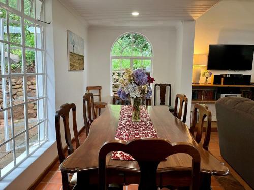 a dining room table with a vase of flowers on it at Woodcroft in Lidgetton