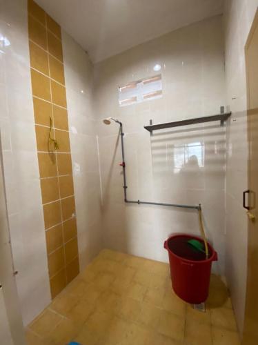 a bathroom with a shower and a red bucket at Homestay Kimanis Papar in Kimanis