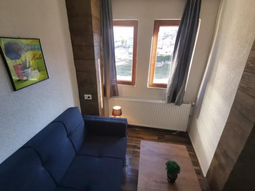 a living room with a blue couch and two windows at Villa ANA-Mavrovo in Mavrovo