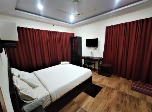 a bedroom with a bed and red curtains and a desk at Peakaavu Cottages in Idukki