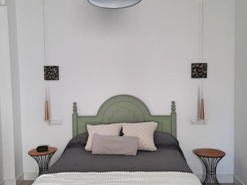 a bedroom with a green bed with two tables at Ático centro Huelva con parking in Huelva
