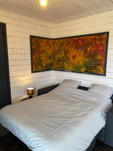 - un lit blanc dans une chambre ornée d'une peinture murale dans l'établissement Chalets CASABELLA, à Casteljaloux