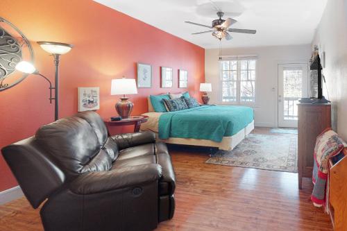 a bedroom with a bed and a leather chair and a couch at Bella Paradiso 04 in Eureka Springs